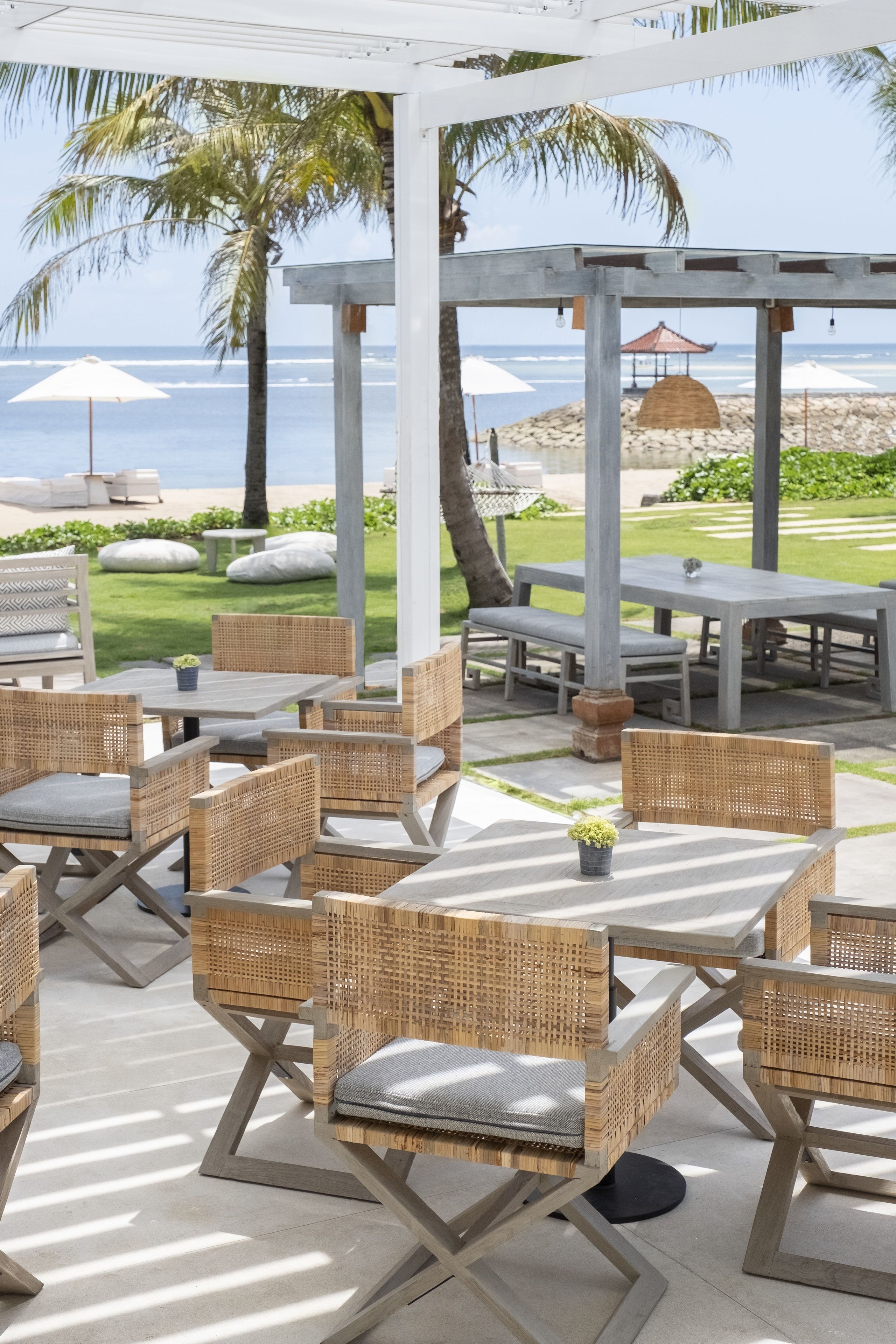 An outdoor seating area with wicker furniture and a view of the beach.