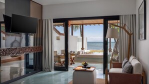 A modern hotel room with a large TV, a dining area with a table and chairs, and a view of the ocean. - Sadara Resort (Nusa Dua)