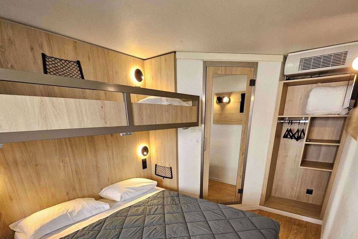 Et lille værelse med køjeseng, et lille natbord og et garderobeskab med plads til at hænge tøj.