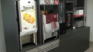 A self-service coffee station with a Tropicana juice dispenser, a Nescafé coffee machine, and various snacks and condiments. - Première Classe Saint Malo - Saint Jouan des Guérets (Saint-Jouan-des-Guerets)