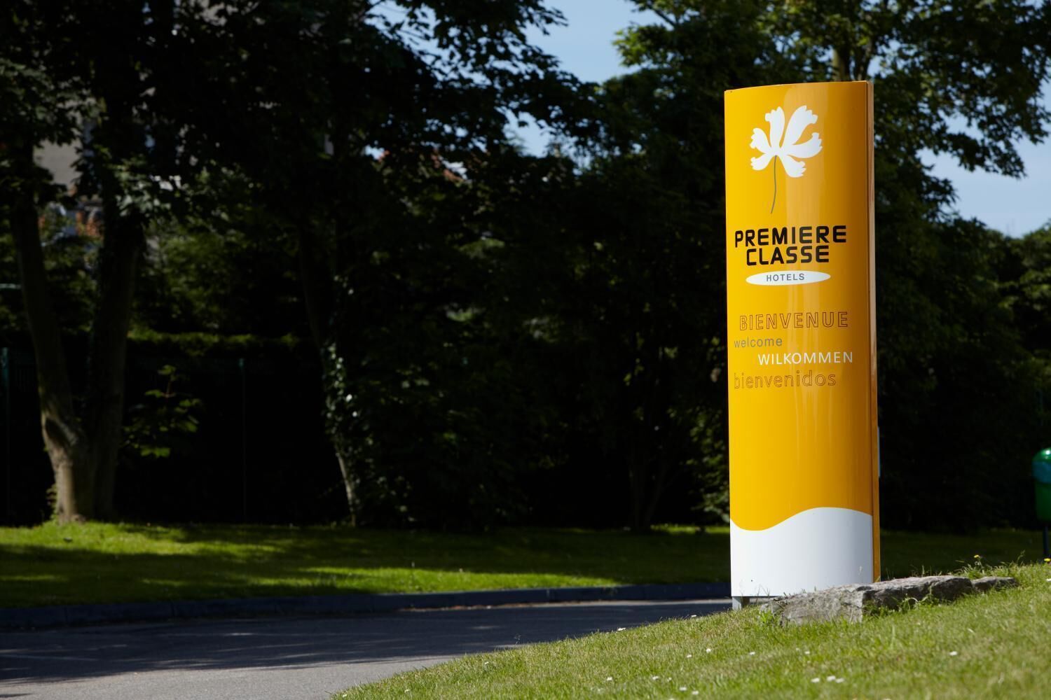 A yellow sign with white text and a white flower symbol, indicating a hotel entrance.