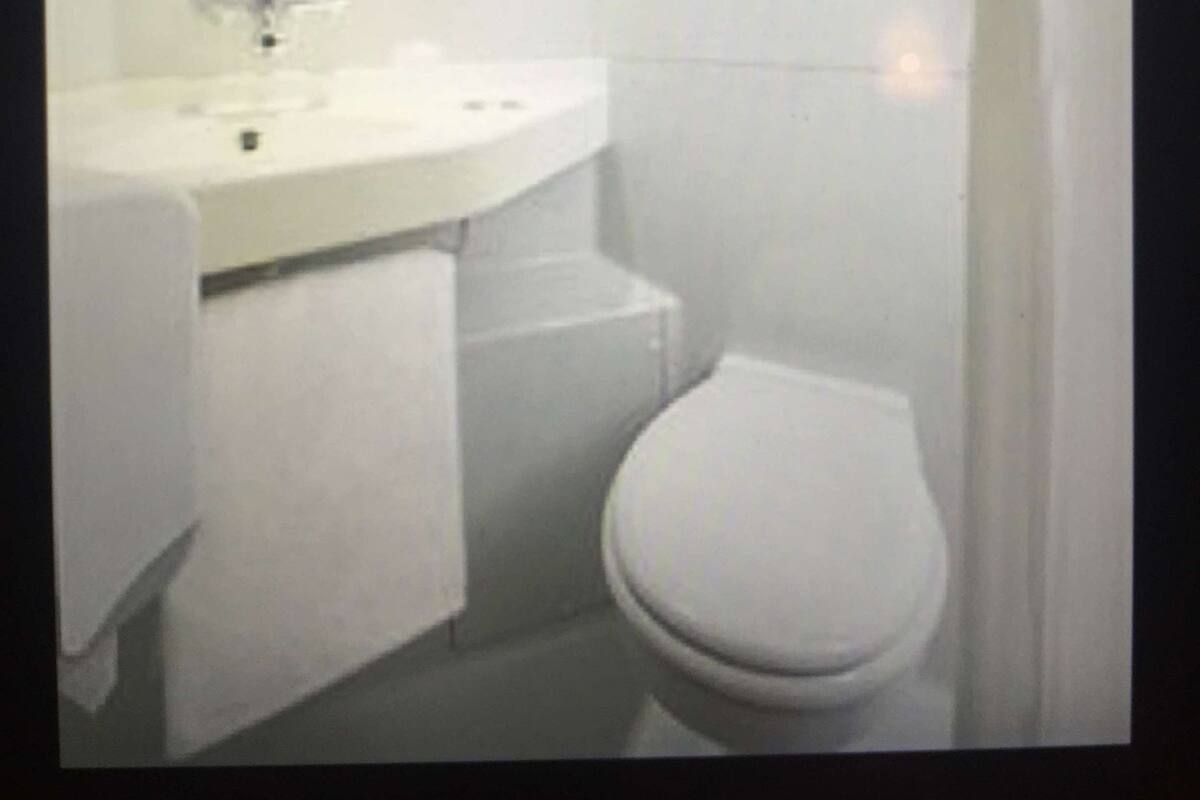 Et badeværelse med hvid vask, spejl og toilet.