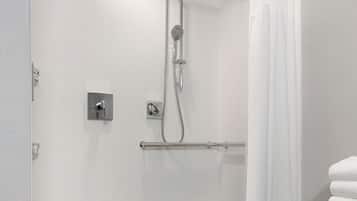 A modern shower with a curved showerhead, a towel rack, and a white shower curtain.