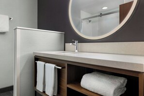 Un baño moderno con un espejo redondo, un lavabo blanco y un perchero para toallas.