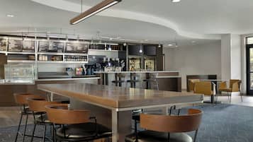 A modern bar area with a long counter, bar stools, and a variety of beverages.