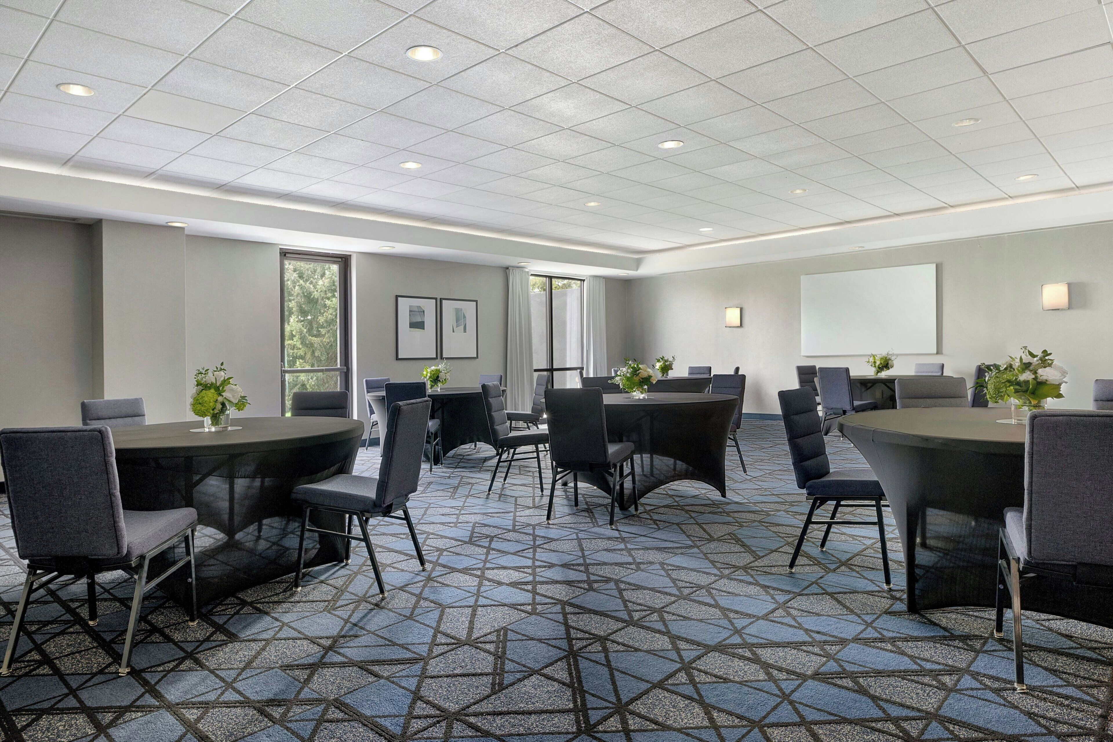 A conference room with a geometric patterned carpet, round tables, and chairs.