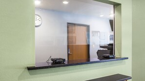 A reception desk with a clock, a door, and a counter with a card reader. - WoodSpring Suites Amarillo East I-40 (Amarillo)
