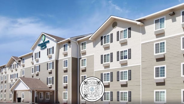 A multi-story hotel with a modern design, featuring a prominent logo on the facade. - WoodSpring Suites Amarillo East I-40 (Amarillo)