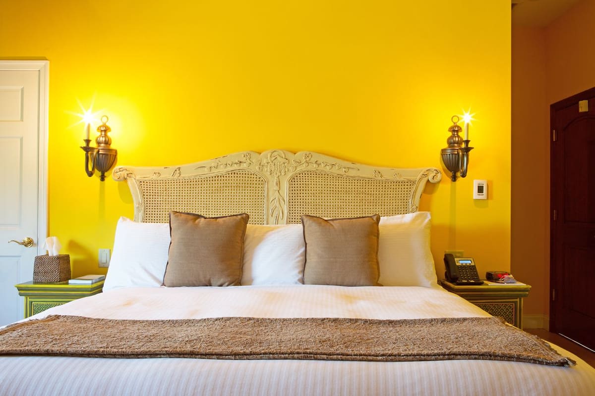 A bed with a white headboard, two bedside lamps, and a bedside table with a telephone and a tissue box.