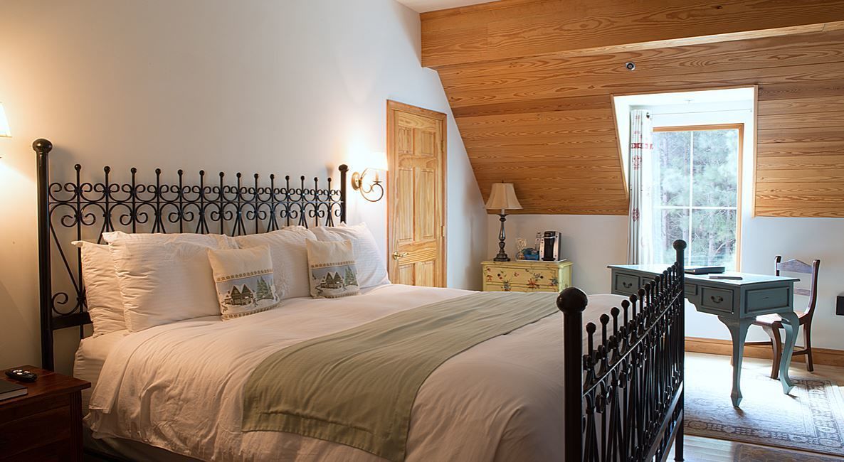 A bedroom with a bed, a nightstand, a dresser, a desk, and a chair.