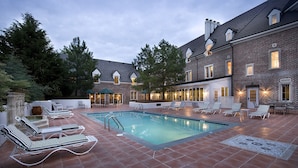 A pool area with lounge chairs and a brick building in the background. - Wedmore Place (Williamsburg)