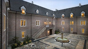 A courtyard with a fountain, brick walls, and a staircase leading to an upper level. - Wedmore Place (Williamsburg)