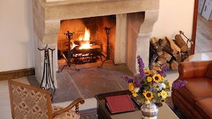 A cozy living room with a stone fireplace, a leather sofa, and a vase of flowers. - Wedmore Place (Williamsburg)