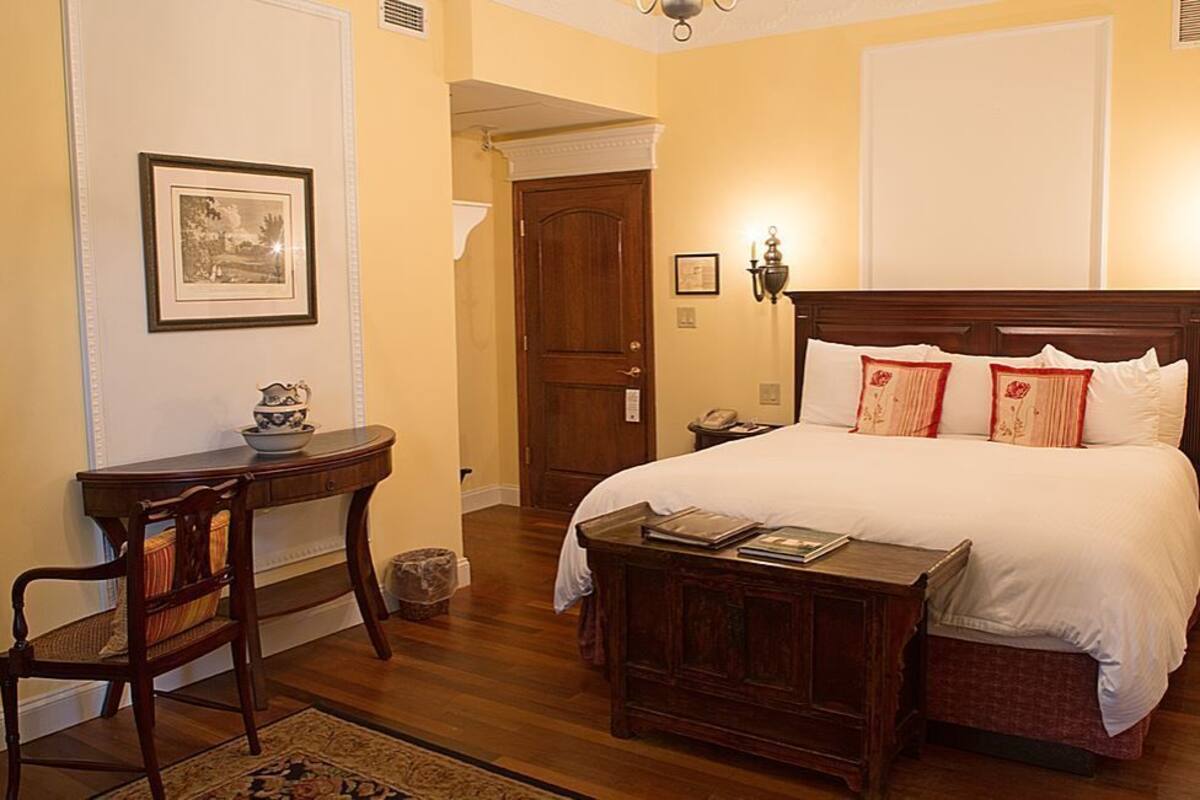 A hotel room with a large bed, a wooden nightstand, a desk, and a chair.