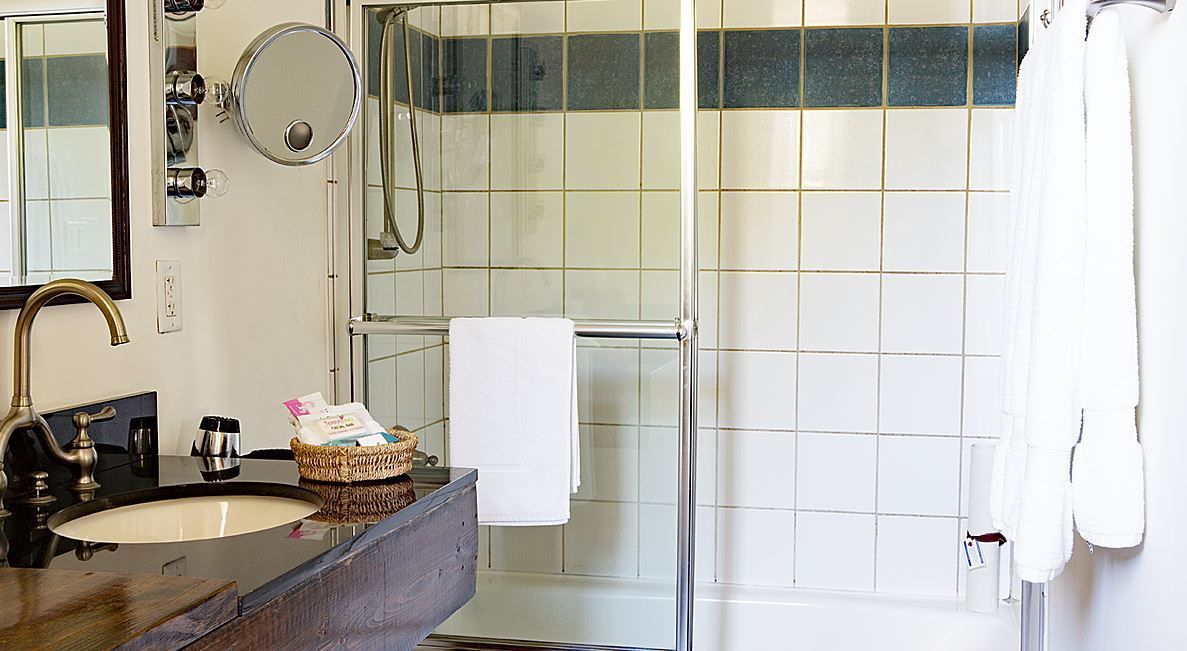A bathroom with a sink, mirror, towel rack, and shower area.