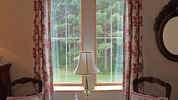 A room with a window, a lamp, two chairs, and a mirror on the wall.