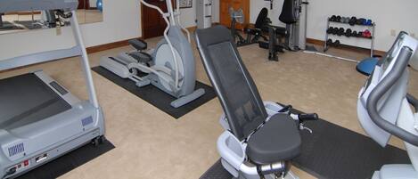 Un gimnasio con equipo de ejercicio, incluyendo cintas de correr, bicicletas estáticas y máquinas de pesas.