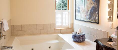 Un baño con una bañera grande, una ventana y un cuadro en la pared.