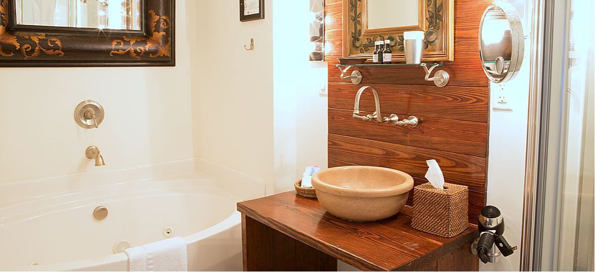 A bathroom with a bathtub, a wooden vanity with a sink, and a mirror.
