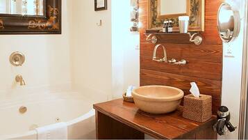 A bathroom with a bathtub, a wooden vanity with a sink, and a mirror.