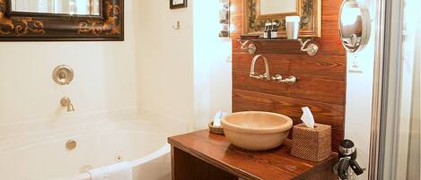 A bathroom with a bathtub, a wooden vanity with a sink, and a mirror.