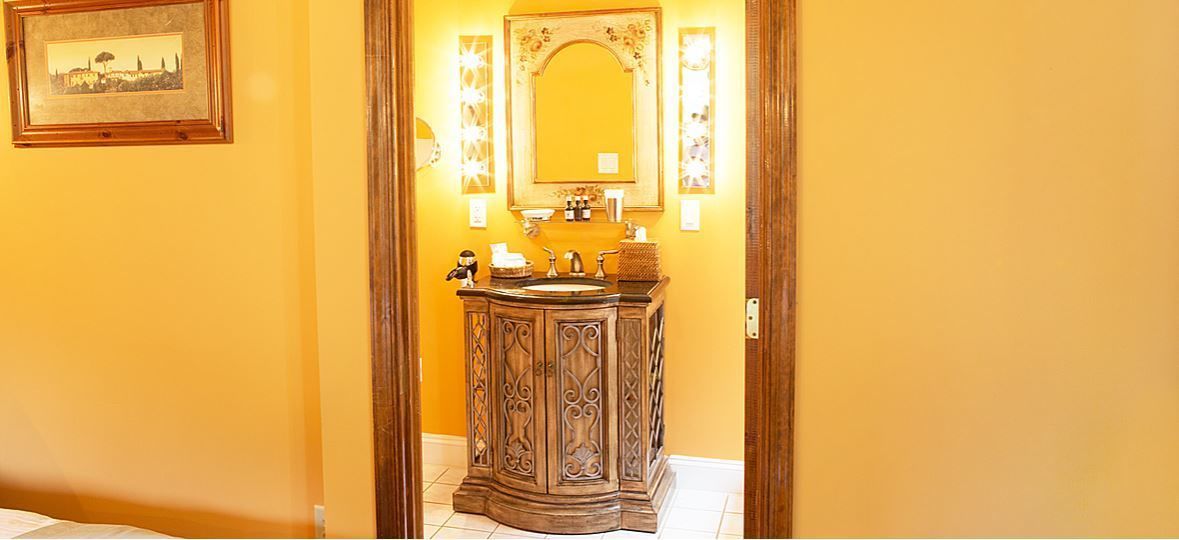 A bathroom with a wooden vanity, a mirror, and a framed picture on the wall.