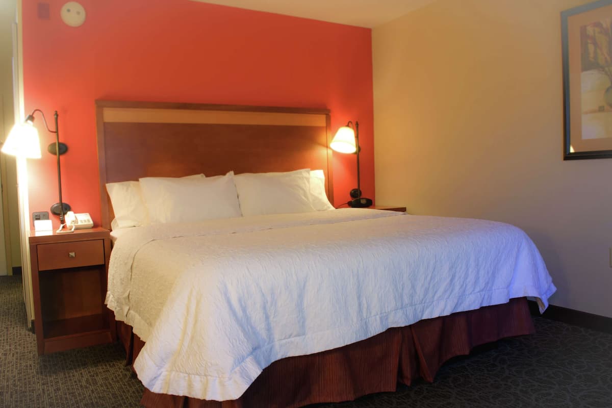 Ein Hotelzimmer mit einem großen Bett, zwei Nachttischen und einem Beistelltisch.