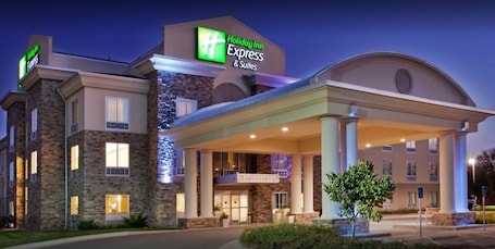 A Holiday Inn Express & Suites building with a stone facade, large entrance canopy, and a well-lit exterior.
