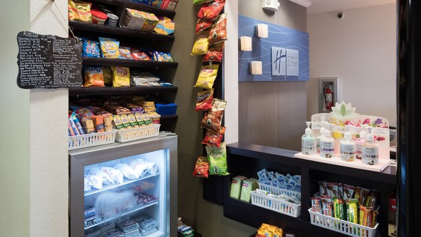 A snack and beverage display with various packaged goods and a refrigerated section. - Holiday Inn Express Hotel & Suites East Wichita I-35 Andover by IHG (Andover)