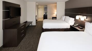 A hotel room with two beds, a TV, a desk, and a lamp.