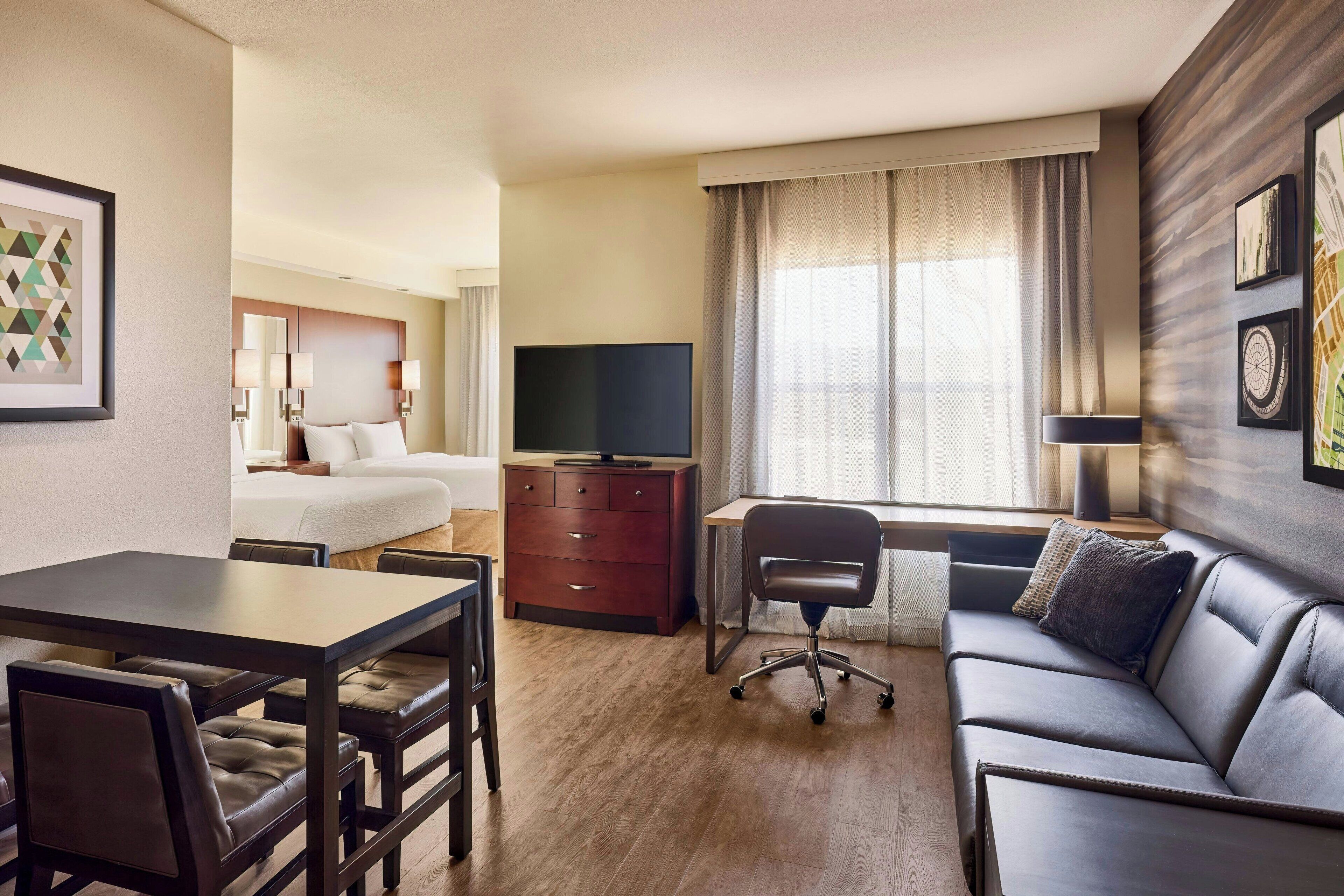 Una habitación de hotel con cama, escritorio, sofá y televisión.