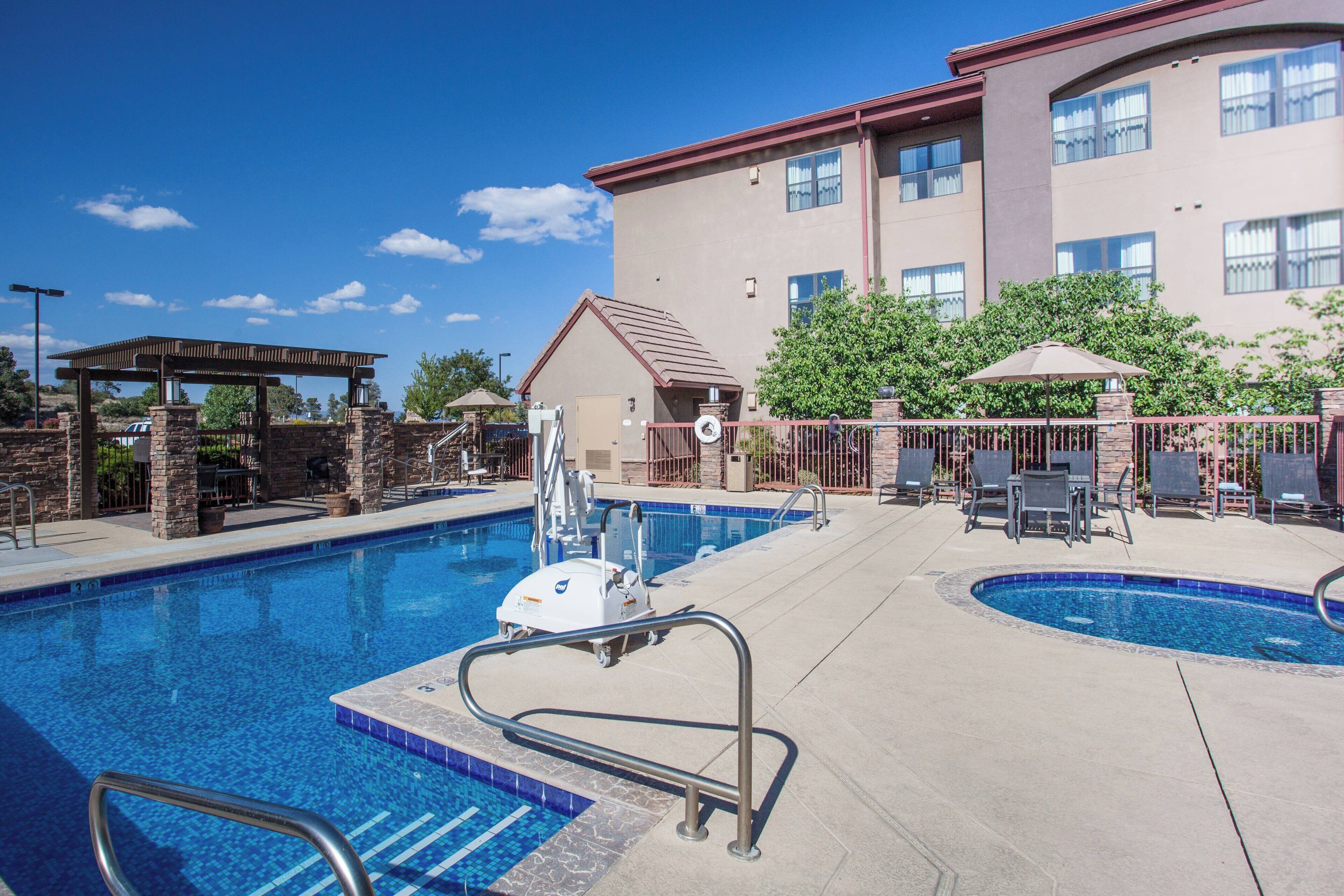 A swimming pool with a lifeguard stand, lounge chairs, and a covered patio area.