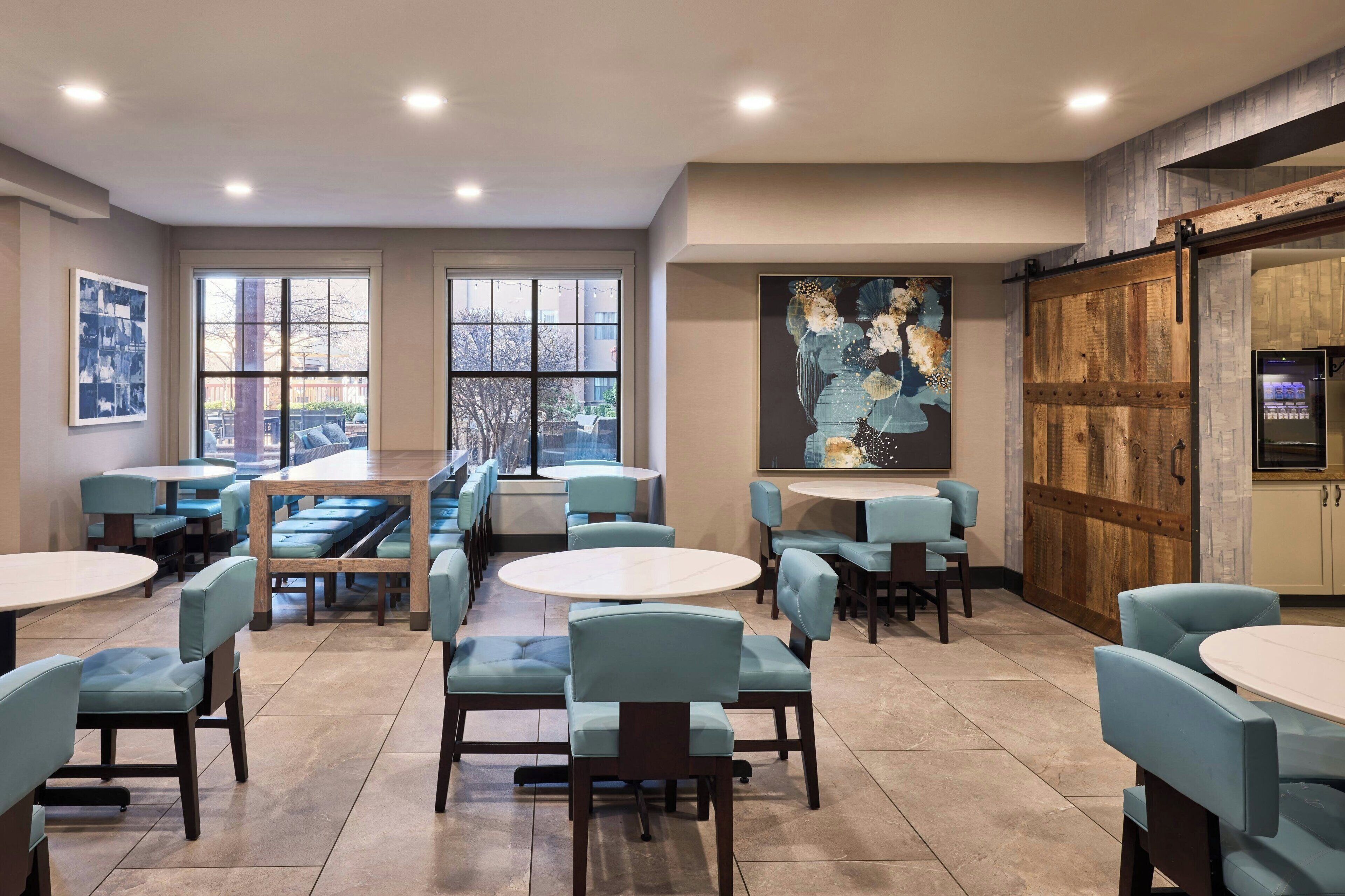 A restaurant with booths and tables, large windows, and a mural on the wall.