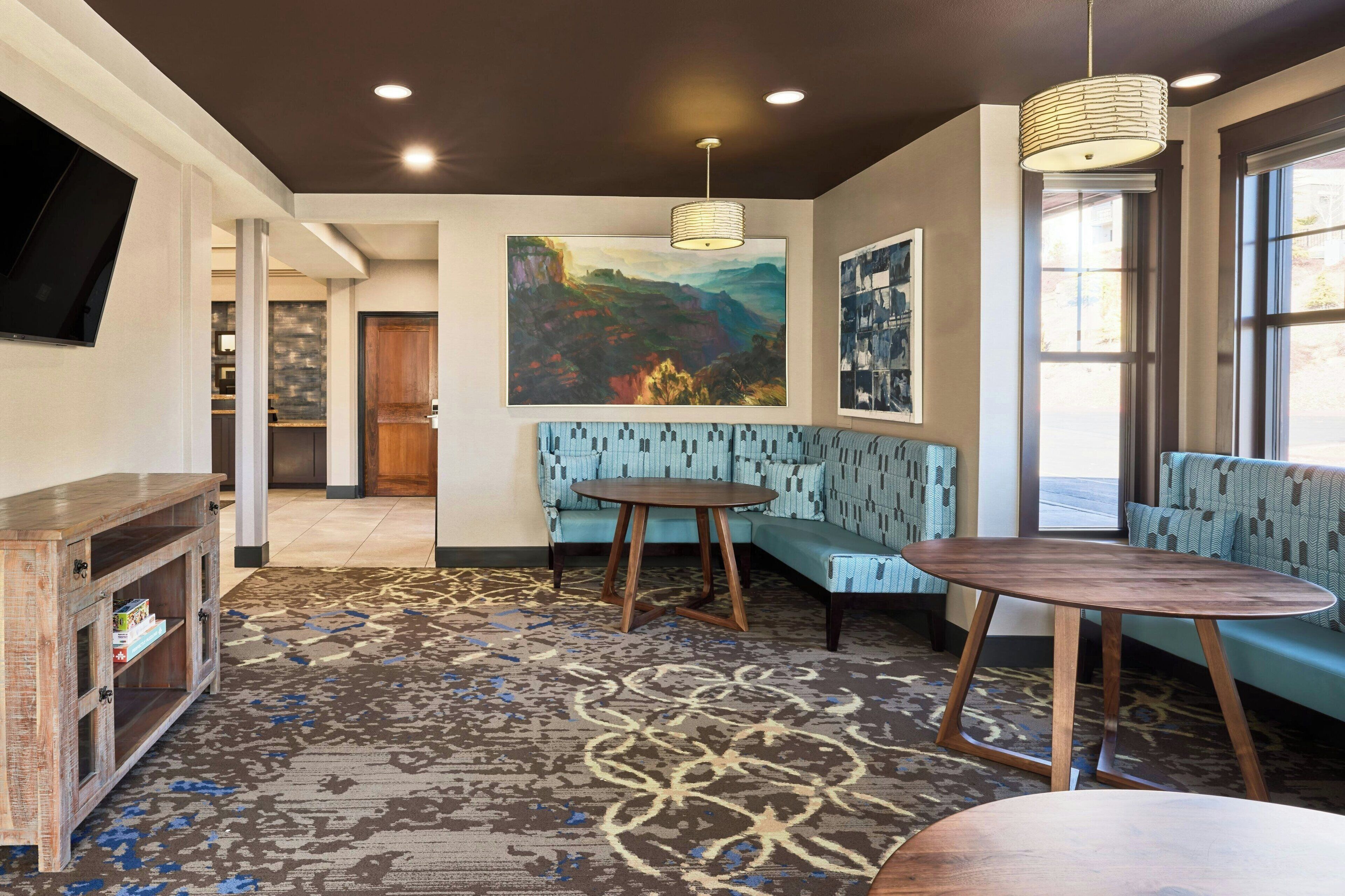 A modern interior with a blue patterned sofa, a round wooden table, and a large painting on the wall.