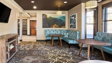 A modern interior with a blue patterned sofa, a round wooden table, and a large painting on the wall.