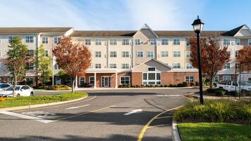 A multi-story hotel with a central entrance, a parking lot, and a street lamp.