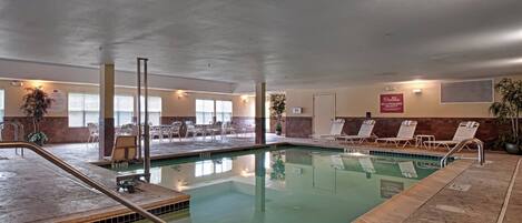 Una piscina interior con sillas de descanso y un letrero de salvavidas.