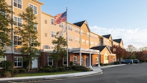 A multi-story hotel with a brick facade, a flagpole with an American flag, and a covered entrance. - Residence Inn by Marriott Neptune at Gateway Center (Neptune City)