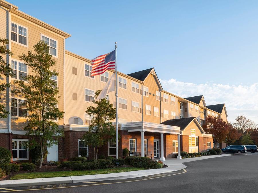 Hotel de vários andares com fachada de tijolos, um mastro com a bandeira americana e uma entrada coberta.