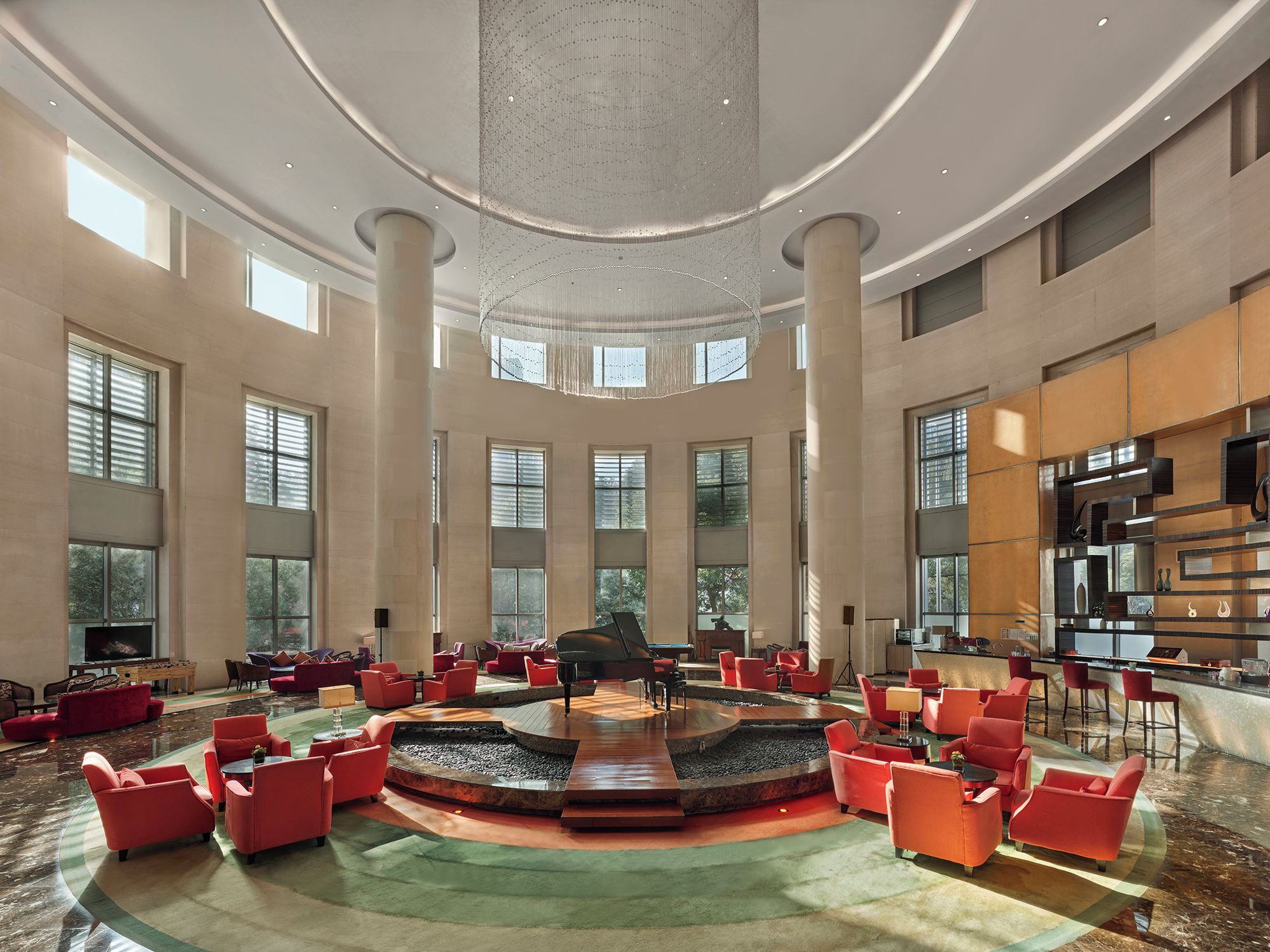 A spacious lobby with a grand piano, multiple seating areas, and large windows.