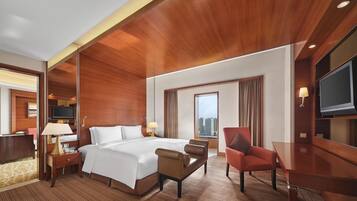 A hotel room with a large bed, a desk, a chair, a TV, and a city view.