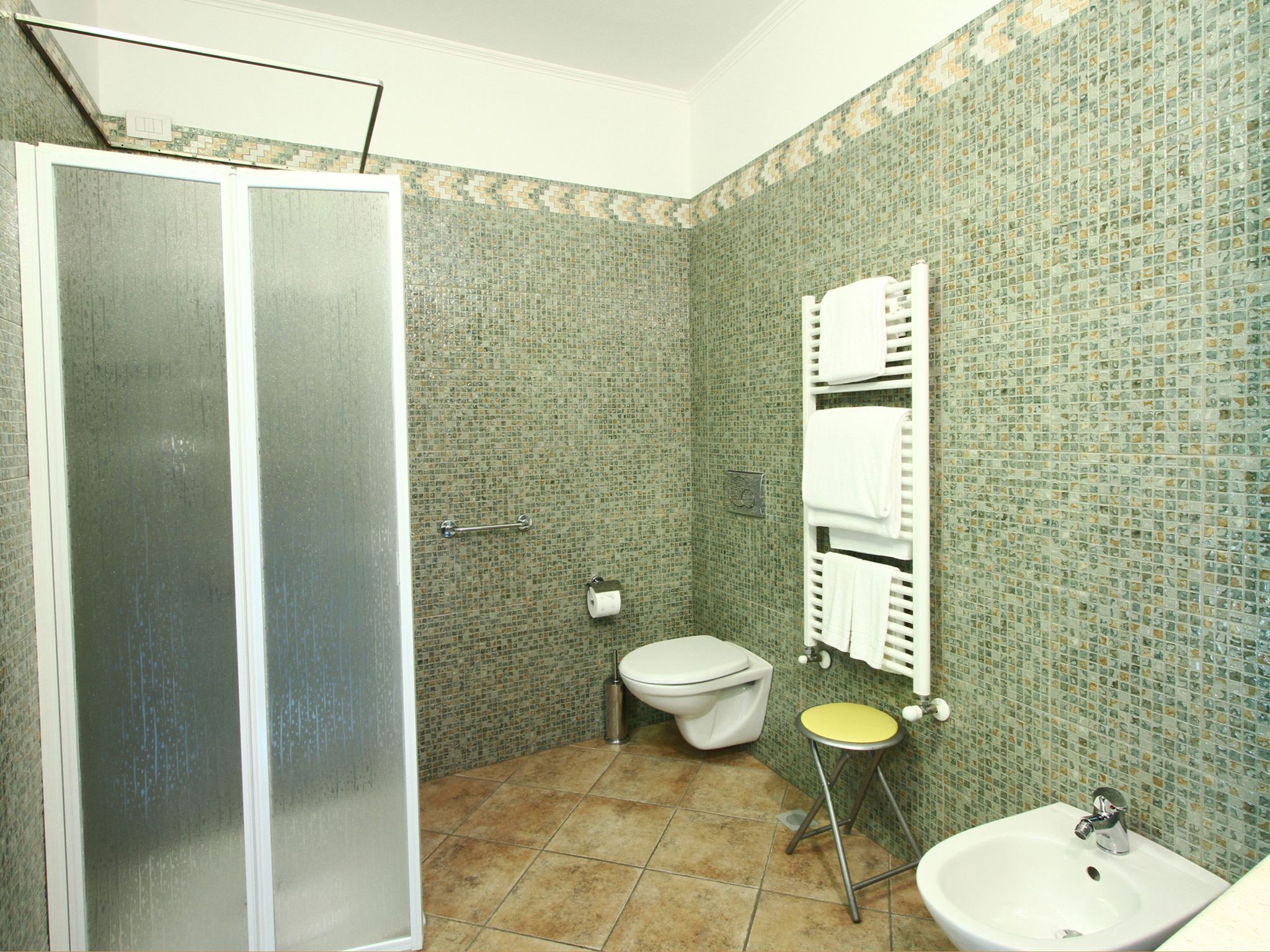 Une salle de bain équipée d’une douche, de toilettes, d’un lavabo et d’un porte-serviettes.