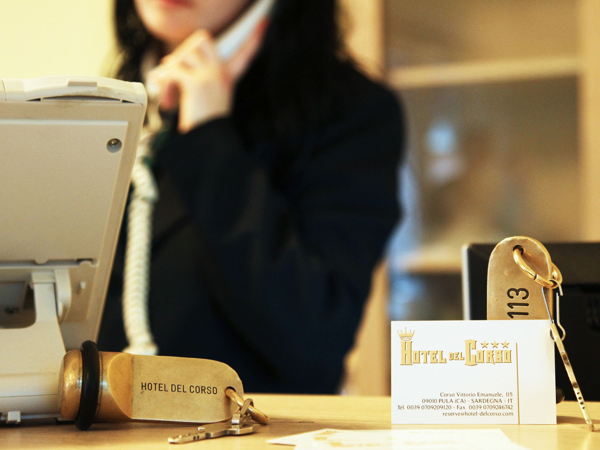 Et hotelreceptionsskrank med en telefon, et nøgleknippe og et visitkort.