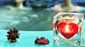 A glass cube with a red heart and a dried flower on a turquoise surface. - Hotel Del Corso (Pula)