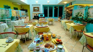 A dining area with multiple tables set for breakfast, featuring a variety of food and drinks. - Hotel Del Corso (Pula)