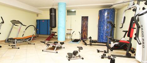 Une salle de sport équipée de machines de cardio, de matériel de musculation et d’un sac de frappe.