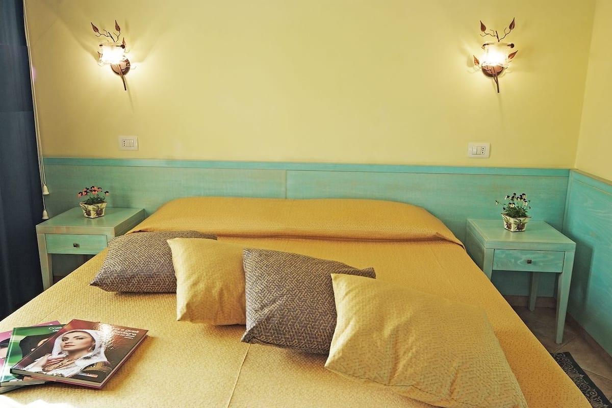 A hotel room with a bed, two bedside tables with lamps, and a magazine on the bed.
