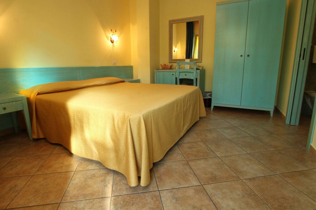 A bedroom with a bed, a nightstand, a dresser, and a mirror.