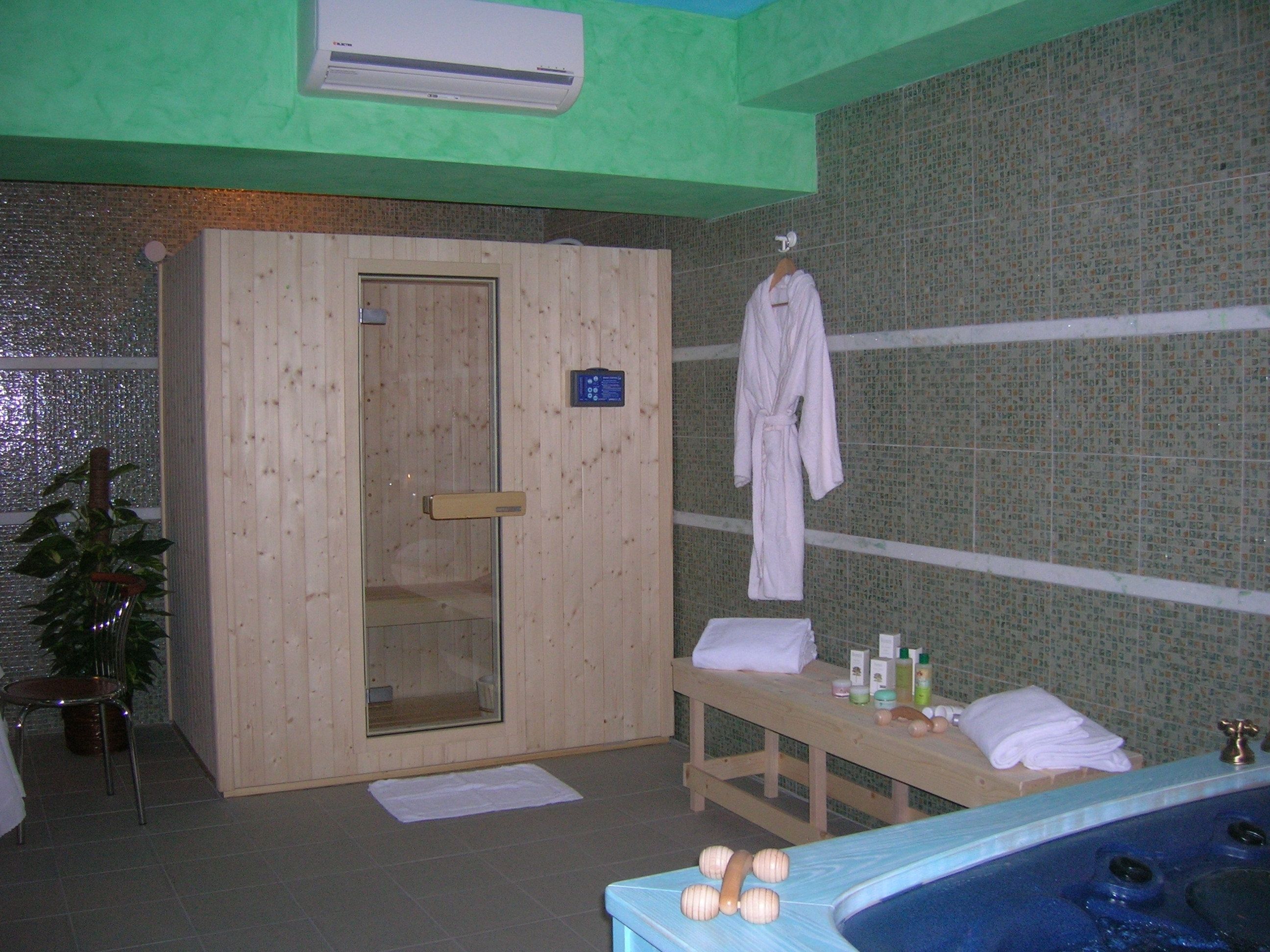 A spa room with a wooden door, a bench with towels, a massage table, and a hot tub.
