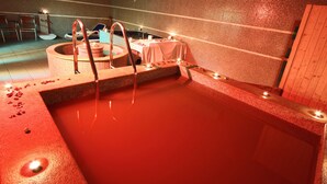 A spa with a hot tub, a massage table, and a small table with candles. - Hotel Del Corso (Pula)